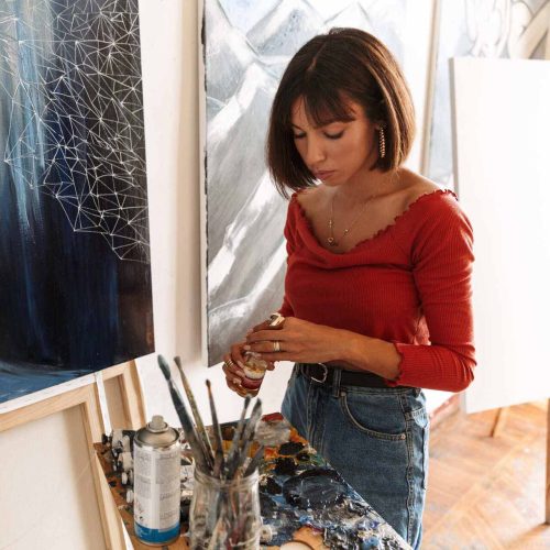 1-portrait-of-young-woman-using-painting-tools-while-2GVZ4TB