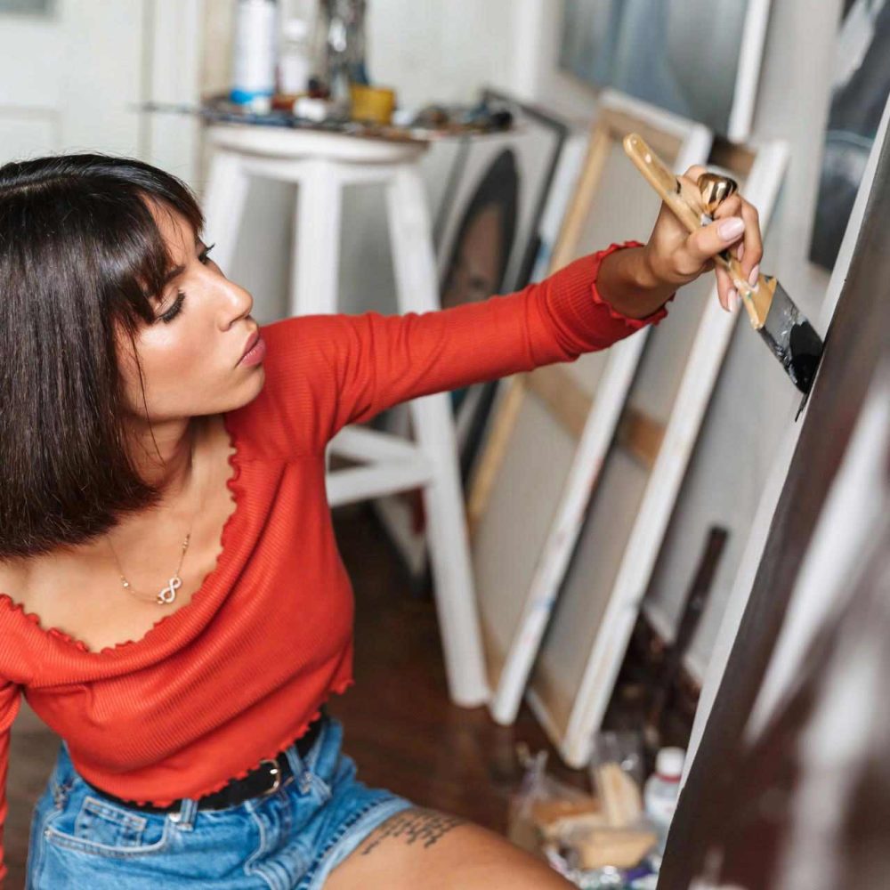 portrait-of-young-woman-using-painting-tools-while-V66ZSVM