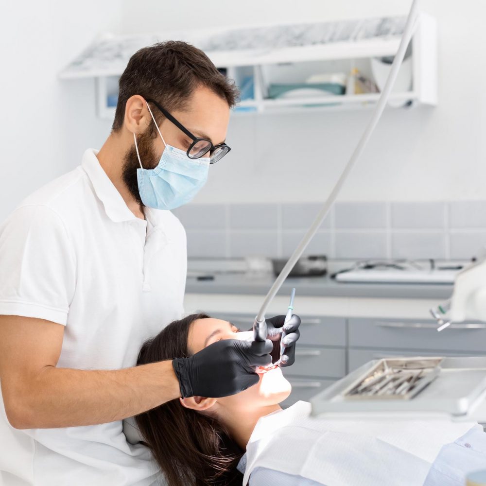 dentist-doctor-in-glasses-filling-teeth-to-female-QGHT5GS