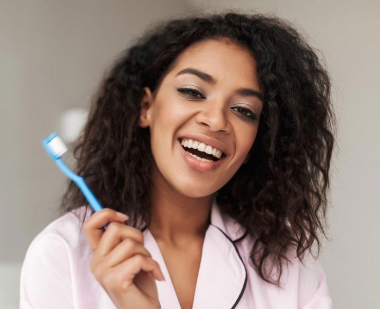 lady-sitting-on-bed-with-toothbrush-in-hand-and-M2E86QA-1