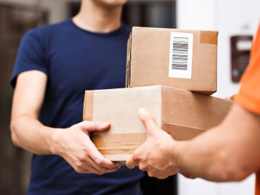 A person wearing an orange T-shirt is delivering parcels to a satisfied client. Friendly worker, high quality delivery service