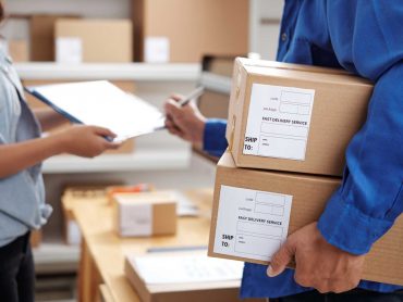 Postman holding parcels and signing for the delivery at post office