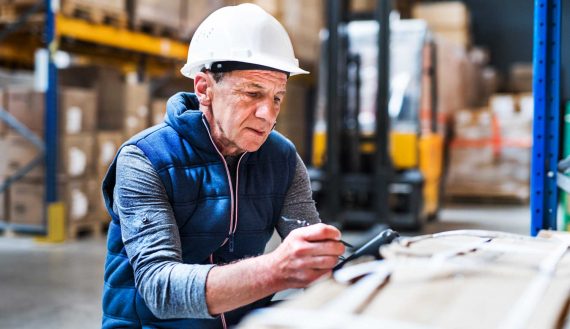 Portrait of a senior male warehouse worker or a supervisor with handheld barcode scanner.
