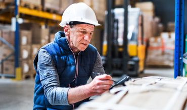 Portrait of a senior male warehouse worker or a supervisor with handheld barcode scanner.