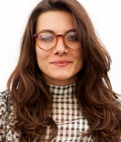 trendy-woman-in-glasses-standing-by-white-wall-5NF8L4S