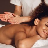 African-american woman getting spa treatment, lying with closed eyes in healthy center