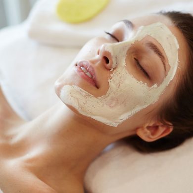Closeup portrait of blissful young woman enjoying beauty treatments and face masks in SPA, lying on massage table with eyes closed