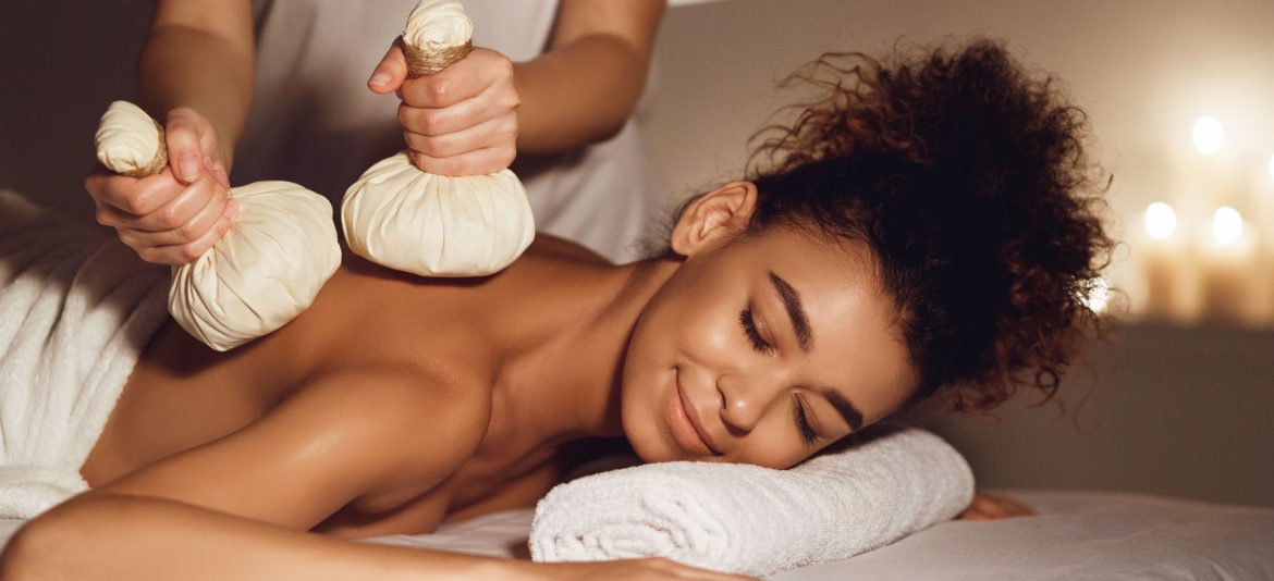 Body care. Woman having massage with hot herbal balls for deep relaxation