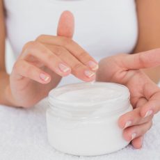 Close up mid section of woman applying cream over white background