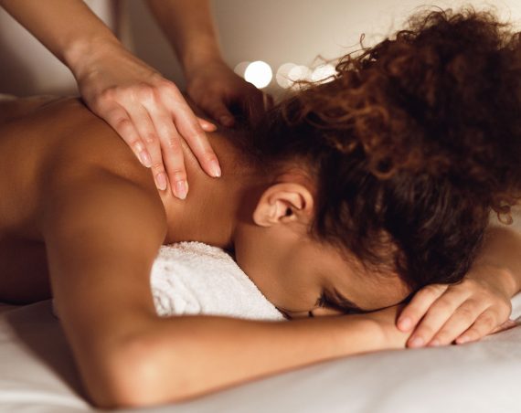Woman enjoying therapeutic neck massage in spa center, closeup