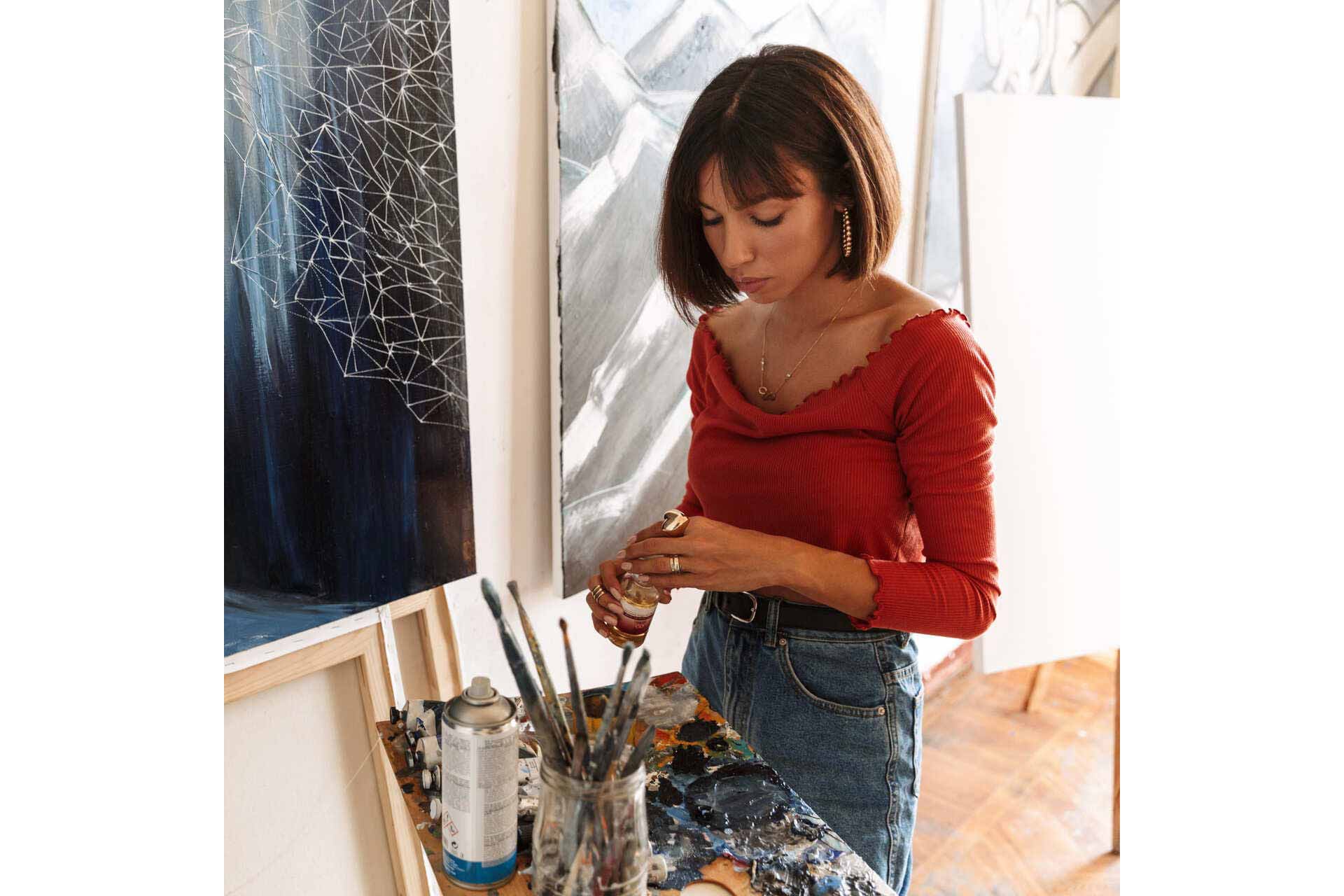 1-portrait-of-young-woman-using-painting-tools-while-2GVZ4TB