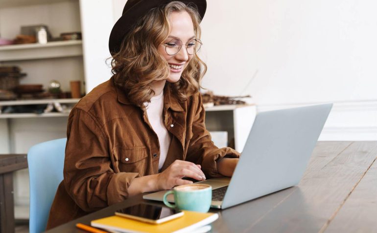 image-of-cheerful-woman-working-with-laptop-while--CNX4RJP
