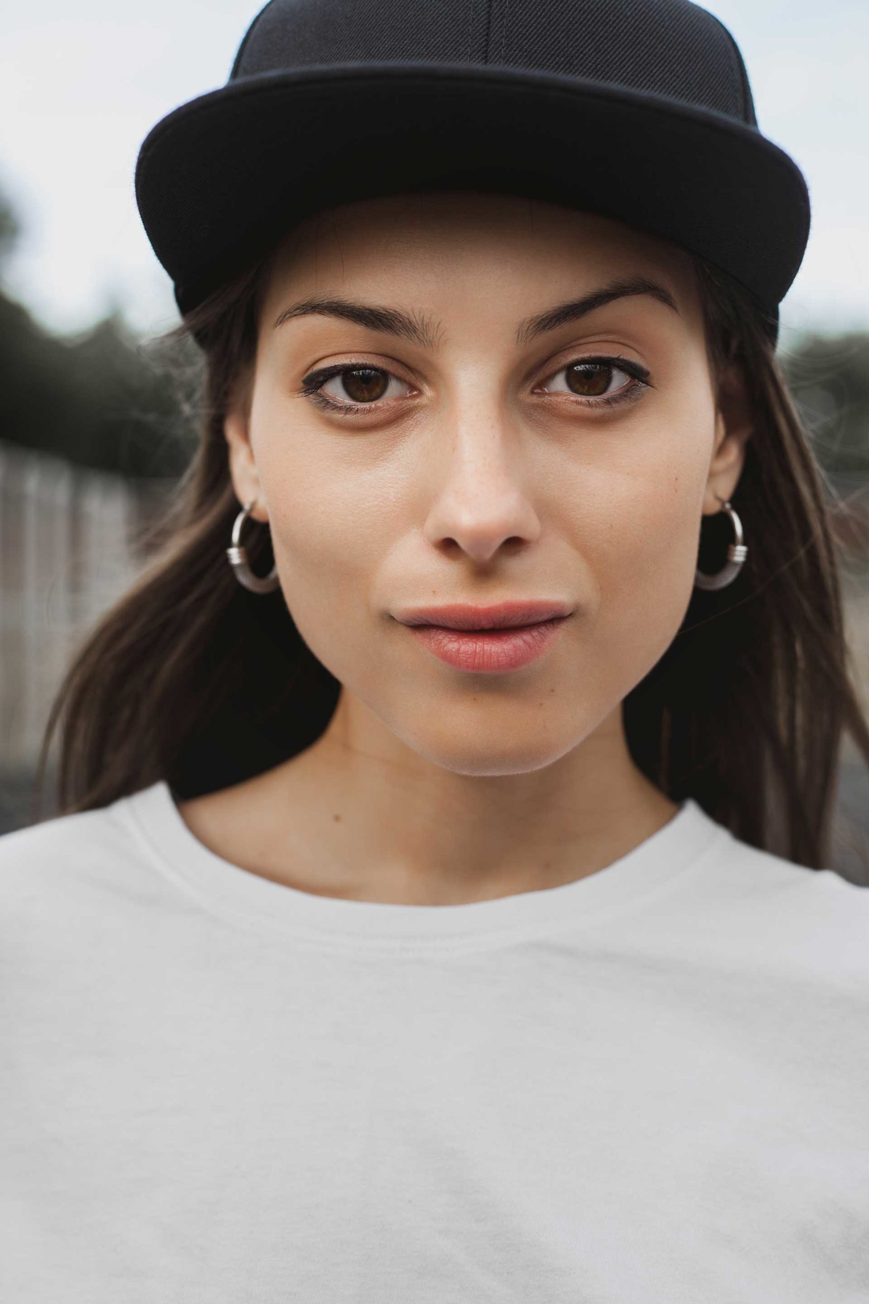 Hipster teen girl posing over urban background. Street swag style, cap, natural long hair, beauty model face