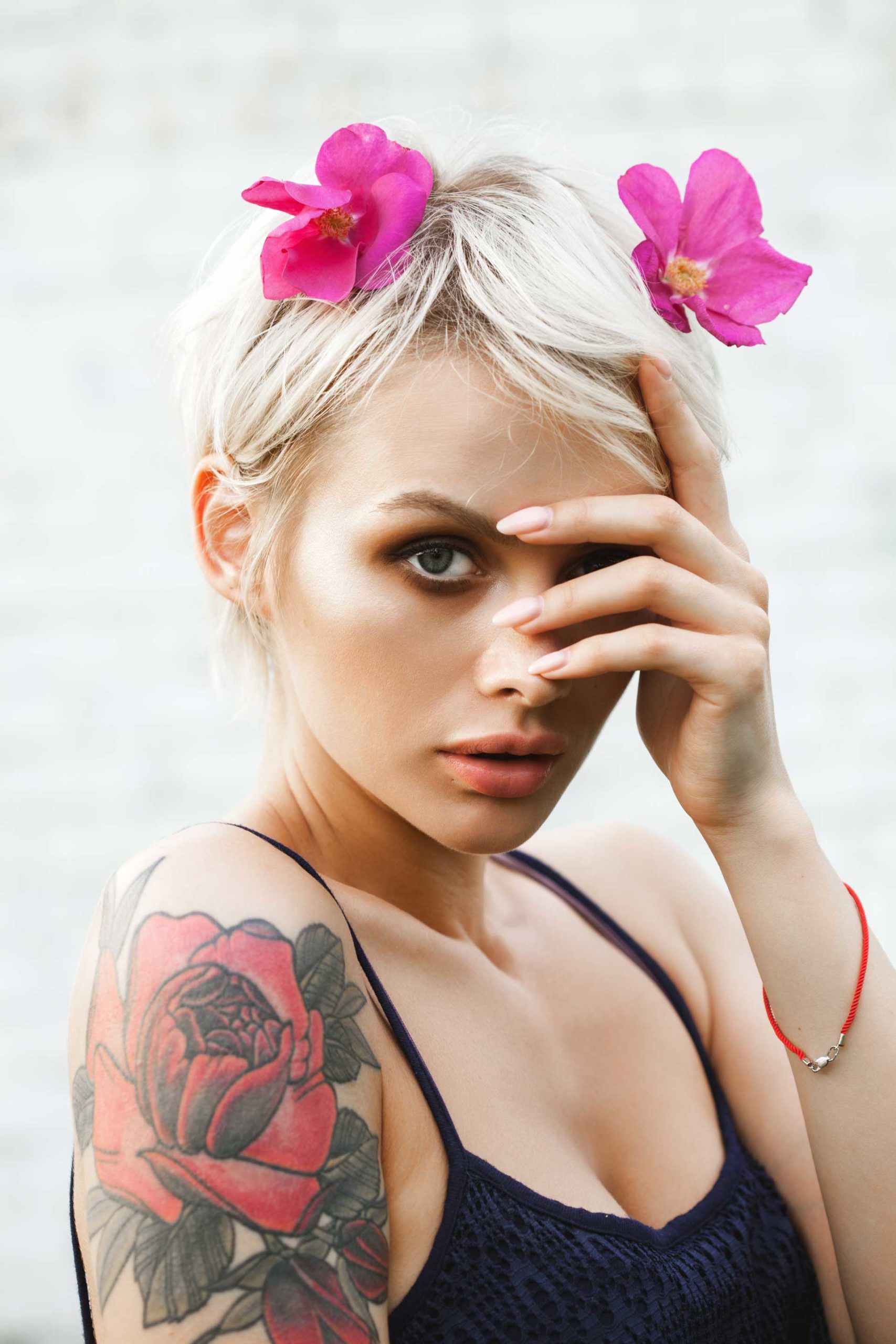 Portrait of young beautiful woman with short blond hair covering her face with her hands